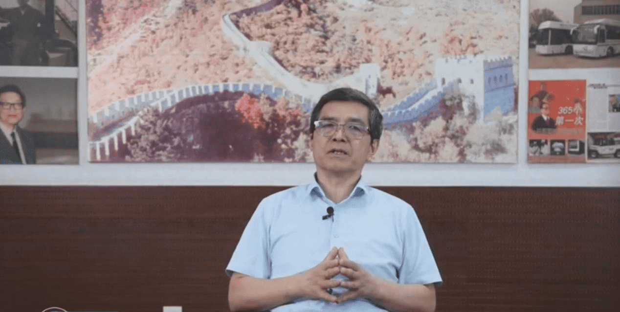 Interview with a speaker seated in front of a Great Wall photograph and vehicle displays.