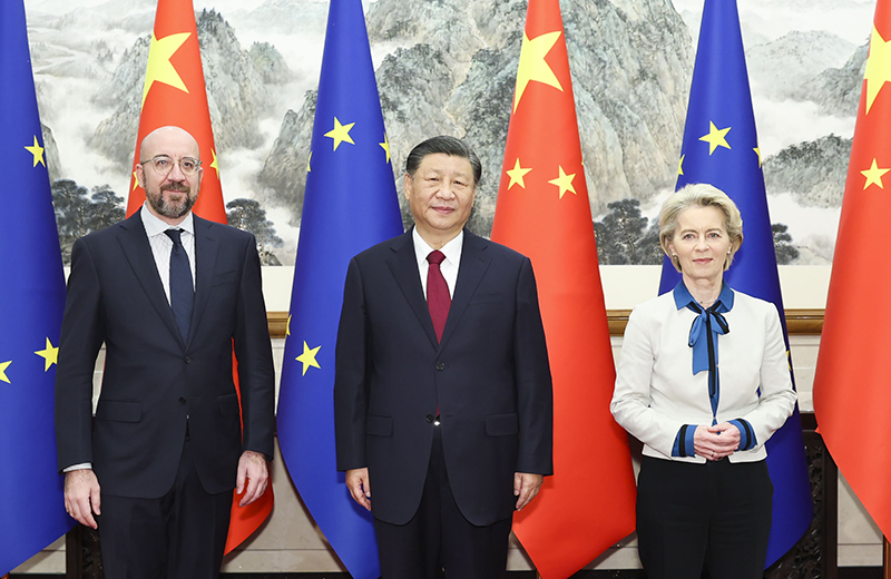 Three officials posing between Chinese and European Union flags.